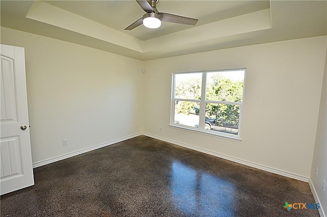 empty room featuring a tray ceiling and ceiling fan