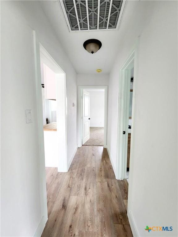 corridor with baseboards, visible vents, and wood finished floors