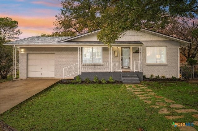 view of front of home with brick siding, a porch, a lawn, driveway, and an attached garage