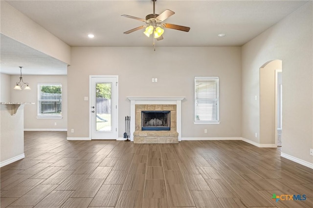 716 Kendra Dr, Temple, TX 76502 - unfurnished living room with arched walkways, wood finish floors, ceiling fan, a stone fireplace, and recessed lighting