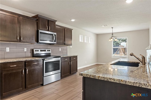 716 Kendra Dr, Temple, TX 76502 - kitchen featuring appliances with stainless steel finishes, decorative backsplash, dark brown cabinets, wood tiled floors, and light stone countertops