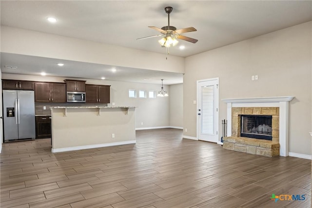 716 Kendra Dr, Temple, TX 76502 - kitchen featuring appliances with stainless steel finishes, a breakfast bar area, open floor plan, light wood-style floors, and dark brown cabinetry