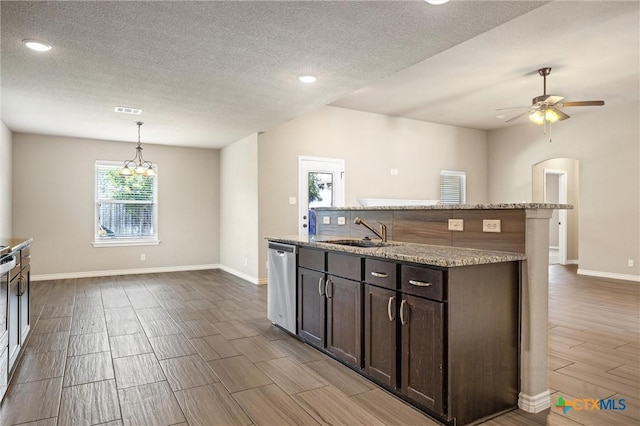 716 Kendra Dr, Temple, TX 76502 - kitchen with stainless steel dishwasher, wood tiled floors, dark brown cabinetry, a kitchen island with sink, and a textured ceiling