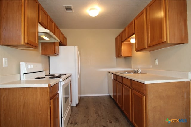 kitchen featuring white appliances, dark hardwood / wood-style floors, and sink