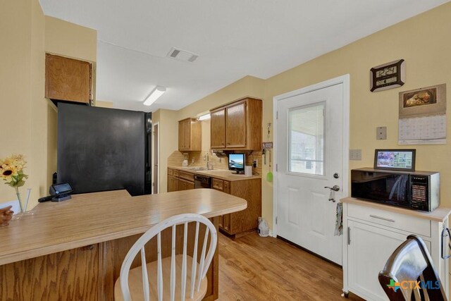 12204 Mustang Dr, Buda, TX 78610 - kitchen with light countertops, black microwave, a peninsula, visible vents, and light wood-style floors