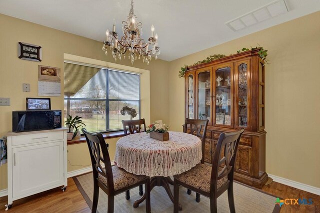 12204 Mustang Dr, Buda, TX 78610 - dining area with baseboards, visible vents, an inviting chandelier, and wood finished floors