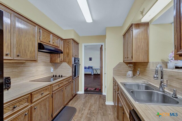 12204 Mustang Dr, Buda, TX 78610 - kitchen featuring light countertops, under cabinet range hood, decorative backsplash, a sink, and black appliances