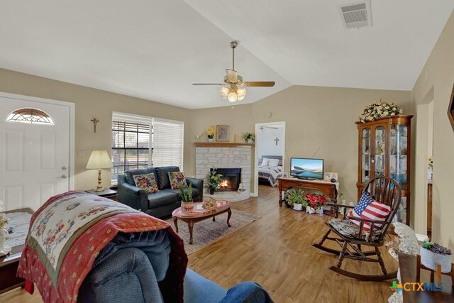 12204 Mustang Dr, Buda, TX 78610 - living area with vaulted ceiling, a brick fireplace, light wood-style flooring, visible vents, and ceiling fan