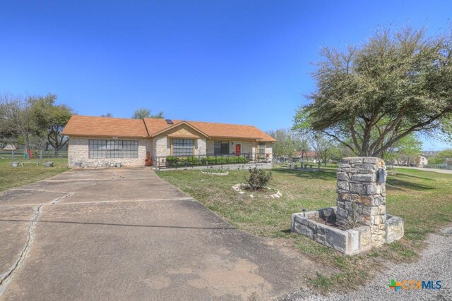12204 Mustang Dr, Buda, TX 78610 - view of front facade featuring stone siding, a front yard, driveway, and a fenced front yard