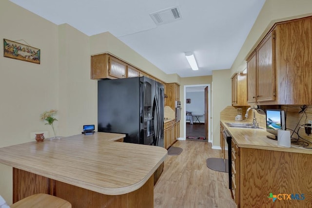 12204 Mustang Dr, Buda, TX 78610 - kitchen featuring light countertops, a sink, a peninsula, black refrigerator with ice dispenser, and visible vents