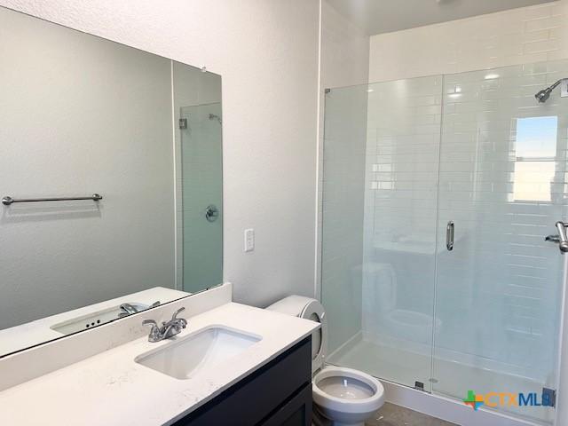 bathroom featuring a shower with door, concrete flooring, and vanity