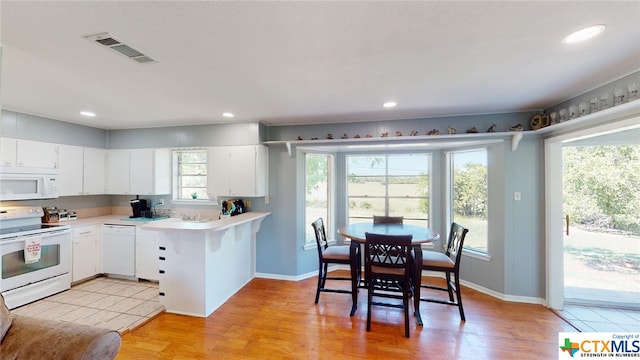 kitchen featuring plenty of natural light, white cabinetry, light wood-type flooring, and white appliances