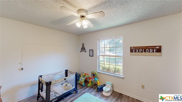 playroom featuring wood-type flooring, a textured ceiling, and ceiling fan