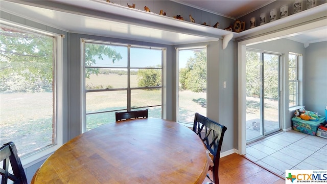 dining area with a wealth of natural light, wood-type flooring, and ornamental molding