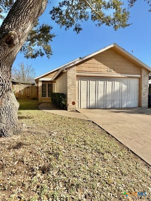 view of home's exterior featuring concrete driveway, brick siding, fence, and an attached garage