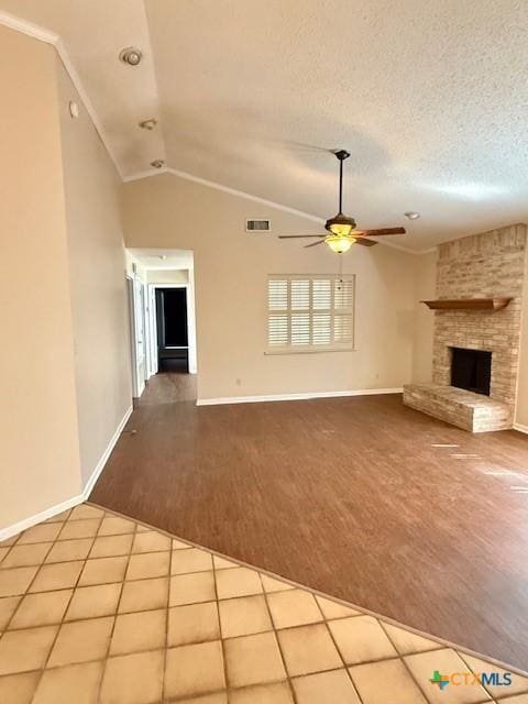 unfurnished living room featuring visible vents, a ceiling fan, a brick fireplace, vaulted ceiling, and a textured ceiling