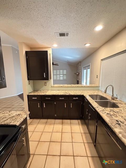 kitchen featuring light stone counters, light tile patterned flooring, a sink, visible vents, and vaulted ceiling