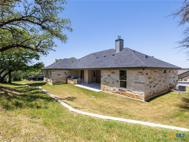 101 Dawna Len Dr, Burnet, TX 78611 - back of property featuring central AC unit, a patio, a chimney, a lawn, and stone siding