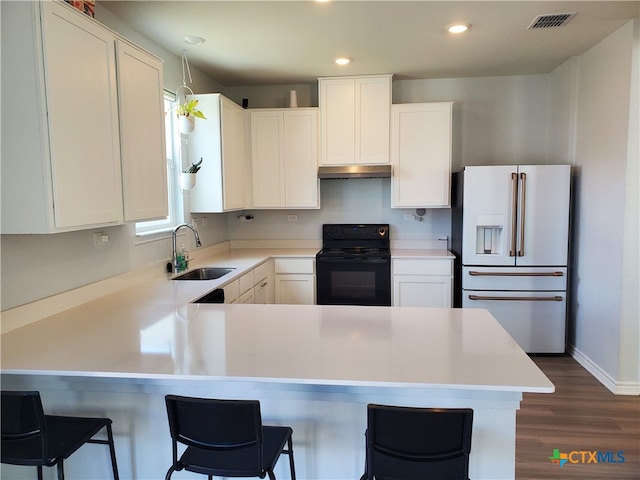 kitchen featuring a kitchen breakfast bar, black / electric stove, white cabinets, and white refrigerator with ice dispenser