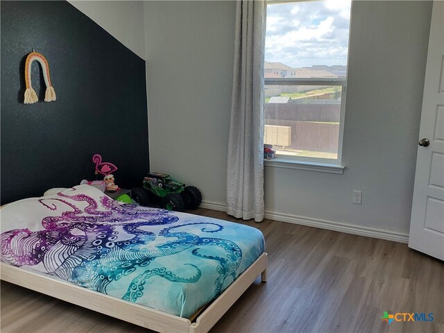 bedroom with hardwood / wood-style floors and multiple windows