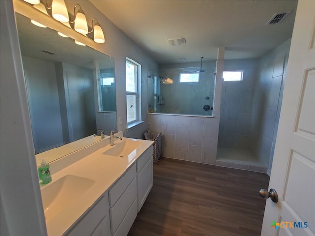 bathroom with hardwood / wood-style floors, vanity, and a tile shower