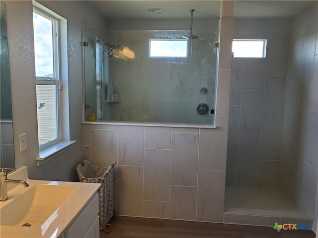 bathroom featuring hardwood / wood-style floors, a healthy amount of sunlight, and a tile shower