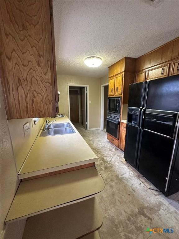 kitchen with black appliances, light countertops, brown cabinets, a textured ceiling, and a sink