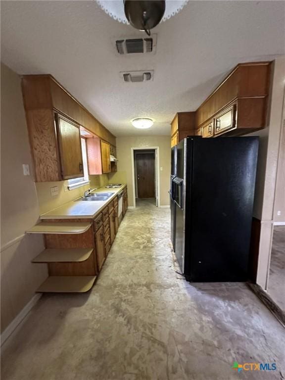 kitchen with a sink, visible vents, black fridge with ice dispenser, and light countertops