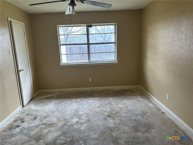 empty room with plenty of natural light, a textured ceiling, concrete floors, and baseboards