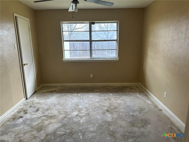 unfurnished room with a textured wall, baseboards, concrete flooring, and a textured ceiling