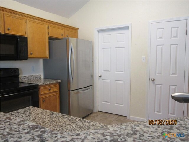 517 Crazy Horse Cir, Harker Heights, TX 76548 - kitchen featuring black appliances, vaulted ceiling, brown cabinetry, light tile patterned floors, and light stone countertops