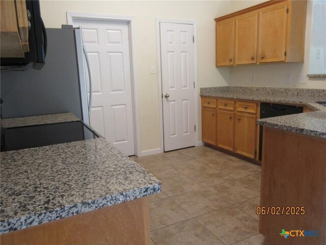 517 Crazy Horse Cir, Harker Heights, TX 76548 - kitchen with freestanding refrigerator, light tile patterned floors, stone counters, and brown cabinetry