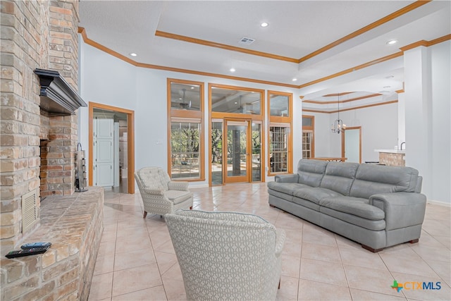 living room featuring a tray ceiling, an inviting chandelier, light tile patterned floors, and ornamental molding