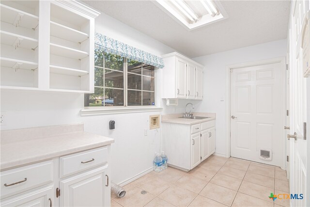 washroom with cabinets, washer hookup, sink, and light tile patterned flooring