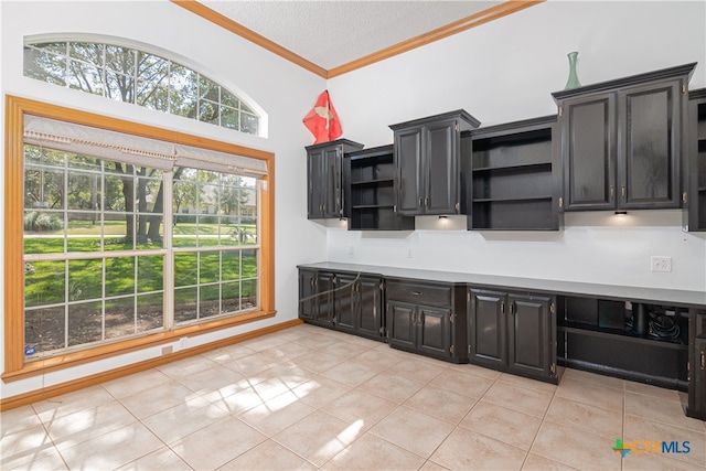 kitchen with high vaulted ceiling, a textured ceiling, light tile patterned floors, and crown molding