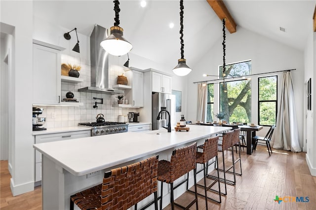 kitchen with light wood-type flooring, a breakfast bar, island range hood, and an island with sink