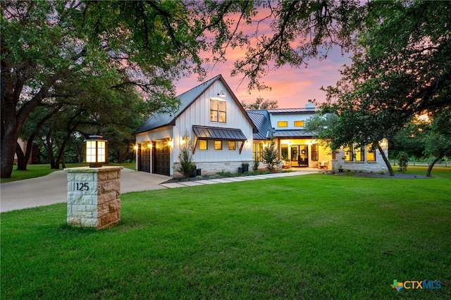 modern farmhouse style home featuring a garage and a lawn