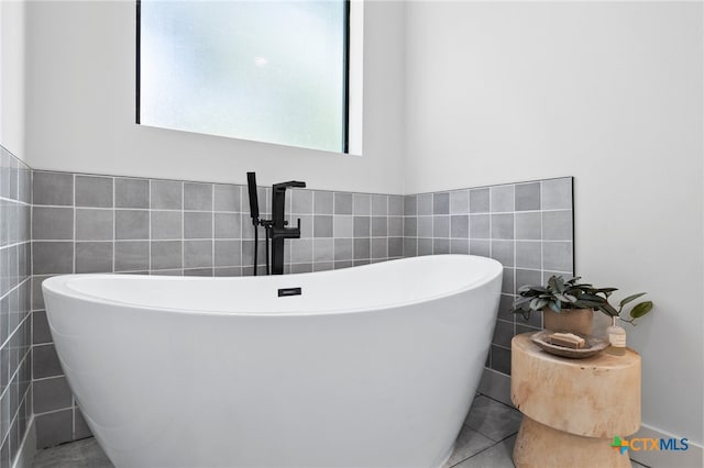 bathroom featuring tile walls, tile patterned flooring, and a tub