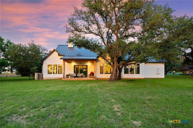 back house at dusk featuring central AC, a yard, and a patio area