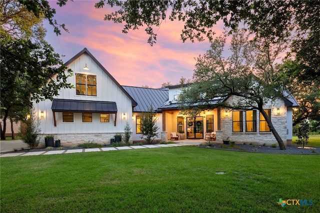 back house at dusk with a lawn