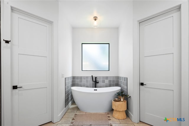 bathroom featuring tile walls, a tub, and tile patterned floors