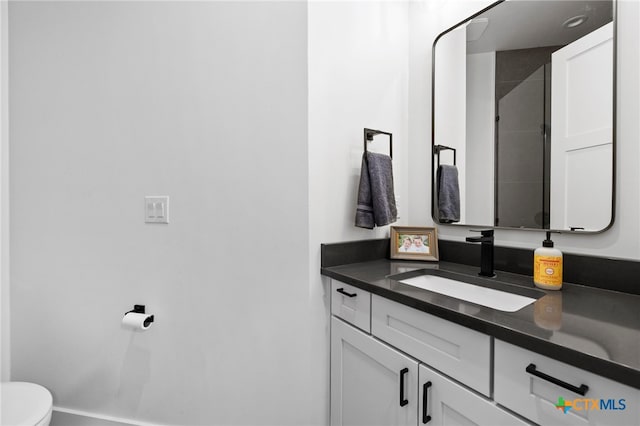 bathroom with toilet, a shower, and vanity