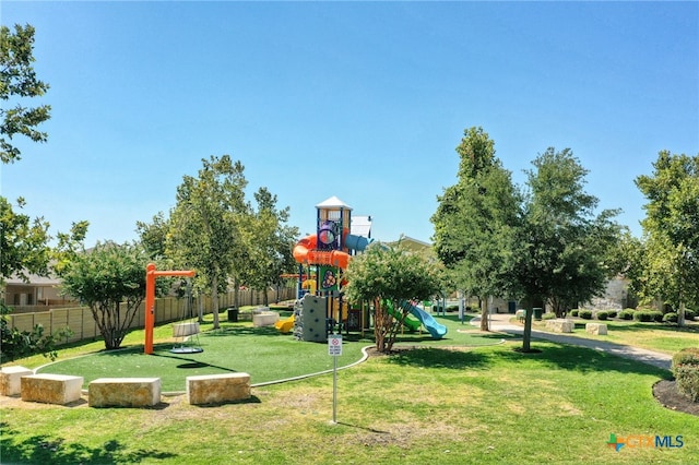 community play area with a lawn and fence