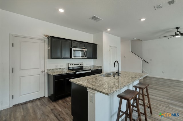 kitchen featuring visible vents, a center island with sink, stainless steel appliances, and a sink