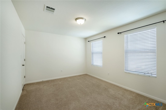 carpeted spare room with visible vents and baseboards