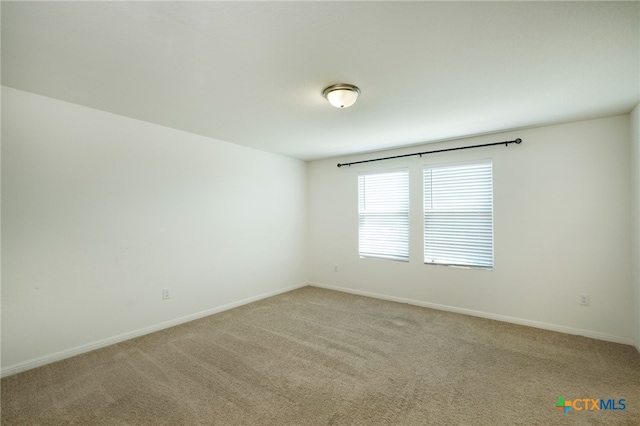 unfurnished room with light carpet and baseboards