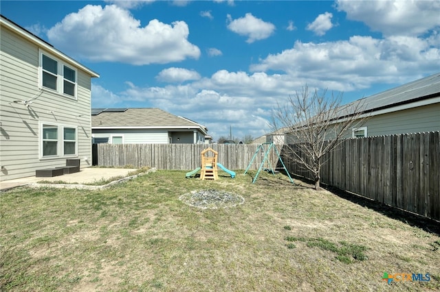 view of yard featuring a patio area, a fenced backyard, and a playground