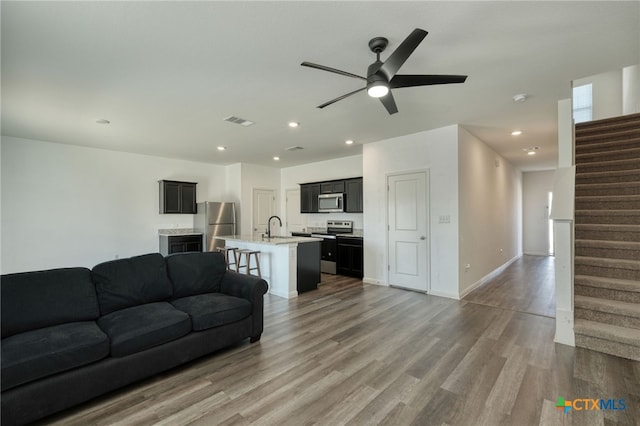 living room featuring visible vents, wood finished floors, recessed lighting, ceiling fan, and stairs