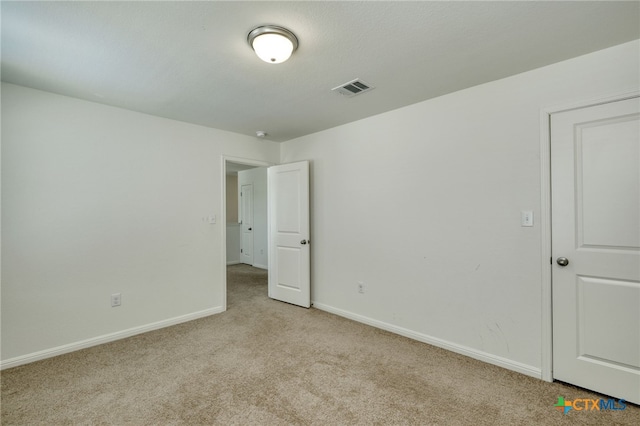 unfurnished bedroom featuring light colored carpet, visible vents, and baseboards