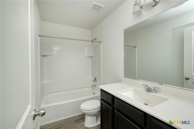 bathroom with visible vents, toilet, shower / bathing tub combination, wood finished floors, and vanity